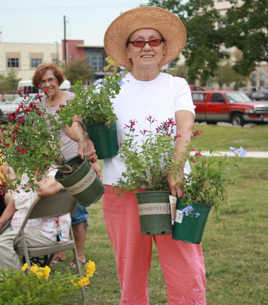 A person holding potted plants in both arms.