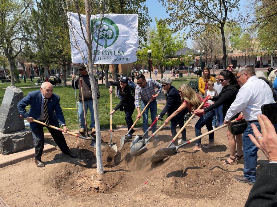 Photo of Arbor Day tree planting event, with participants standing with shovels around a planted tree.
