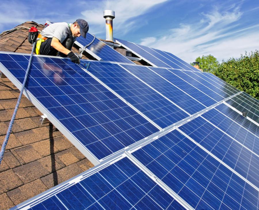 Man installs solar array on roof in summertime.
