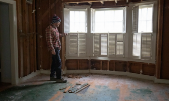 a person stands alone in a home that is in the middle of deconstruction