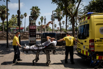 Paramedics help a patient into an ambulance during a heat wave in Barcelona, Spain