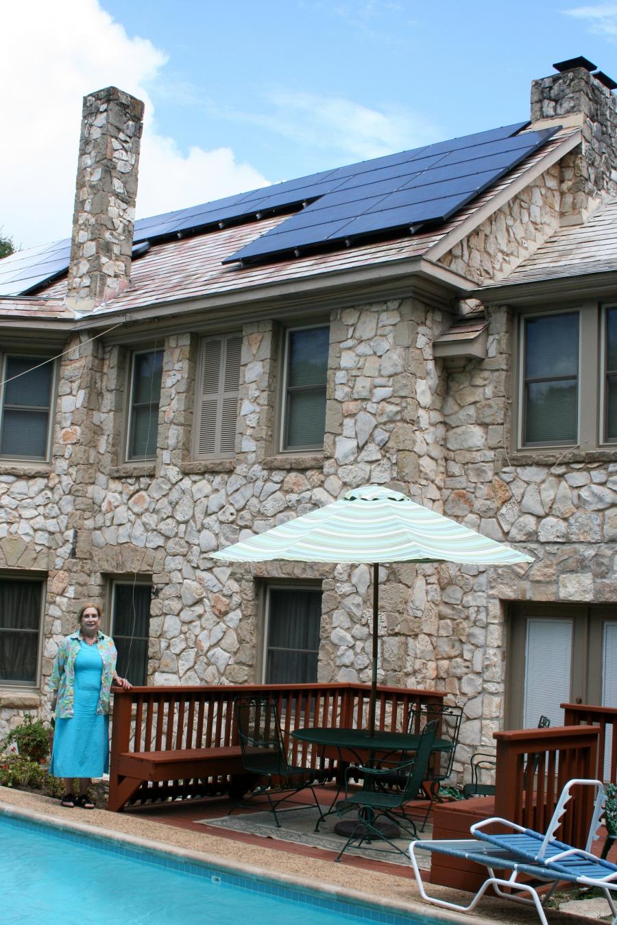 person standing next to a home with solar panels on the roof