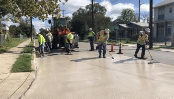 construction workers spreading cool pavement solution onto residential street