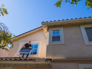 Man installing solar panel on house