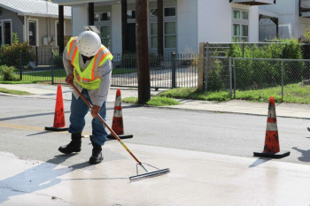 worker spreading cool pavement on street in residential San Antonio