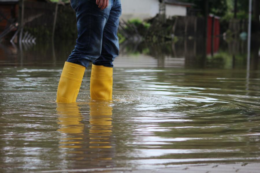 photo of a person wearing yellow rain boots standing in water over their ankles