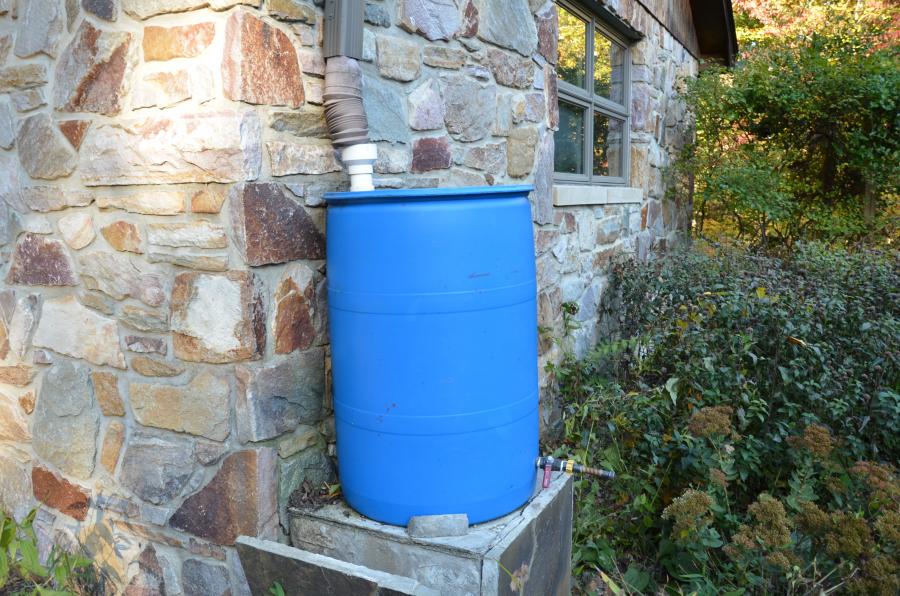 photo of a blue rain barrel connected to a home's downspout