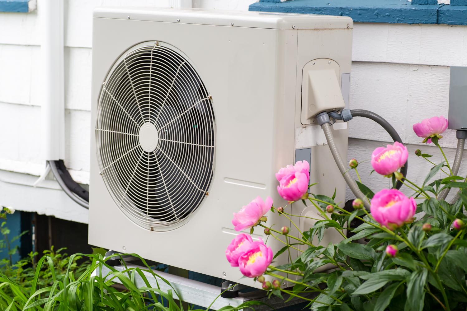 photo of a heat pump with pink flowers near it