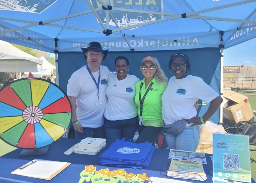 four people posing under a canopy with a wheel to spin and win a prize