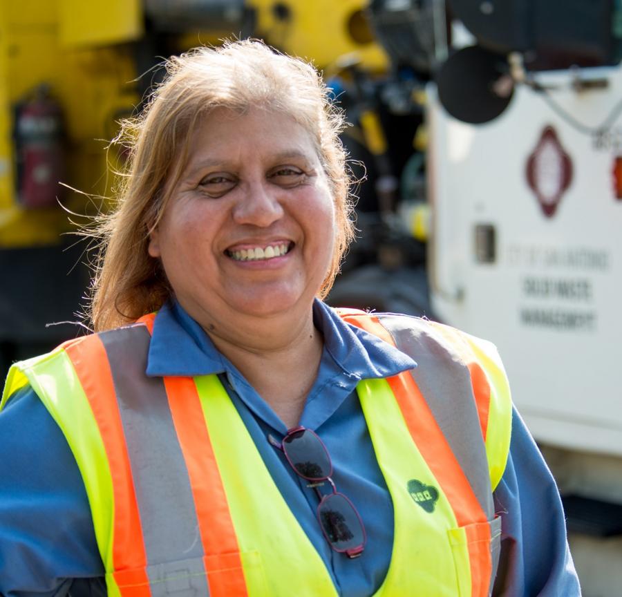 A smiling Solid Waste worker in a safety vest