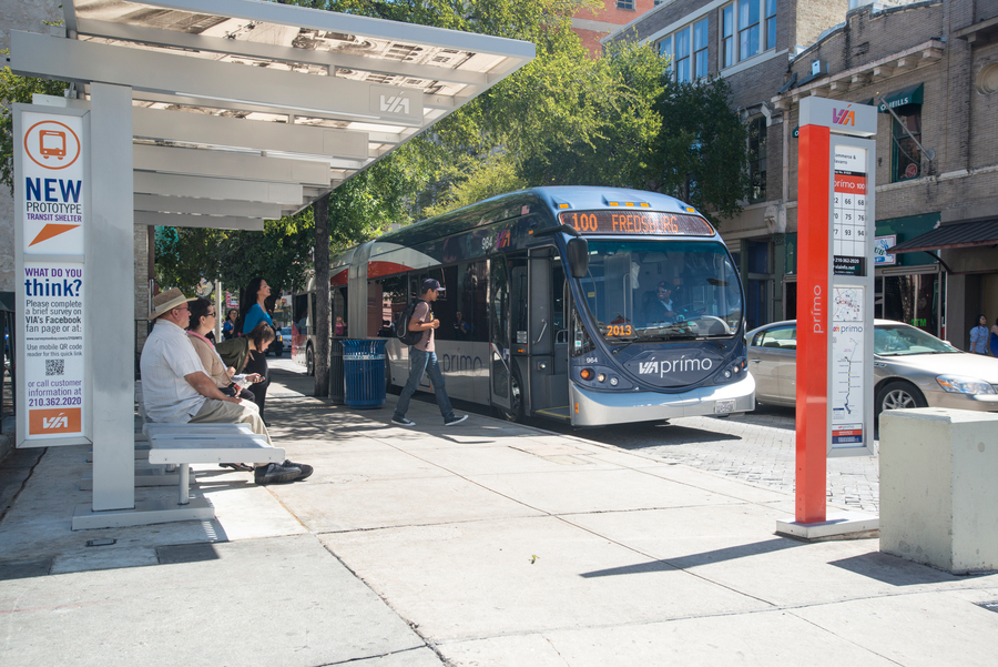 a person boarding a bus stopped at a covered bus stop in a downtown setting