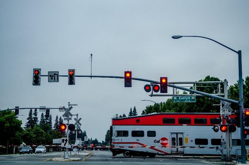 Photo of a train cross through an intersection with many stop lights and warning signs. 