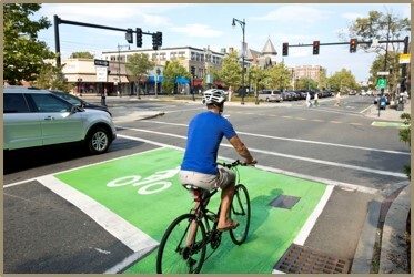 Photo of a person on a bike stopped in a painted bike box at an intersection.