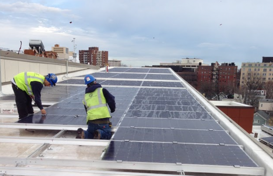Two people working on rooftop solar panels