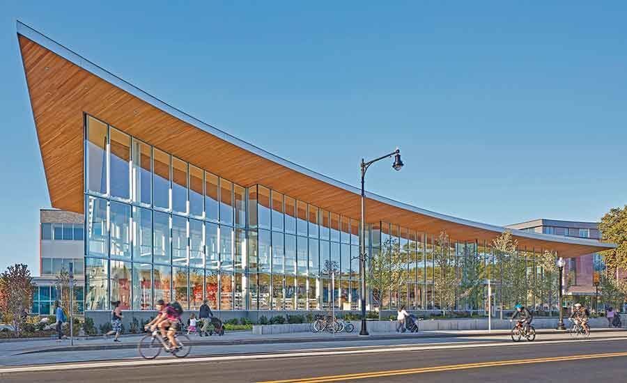 A modern urban school building in spring with people biking and walking. 