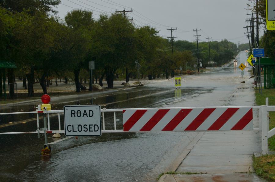 A flooded road with a road closed sign blocking it
