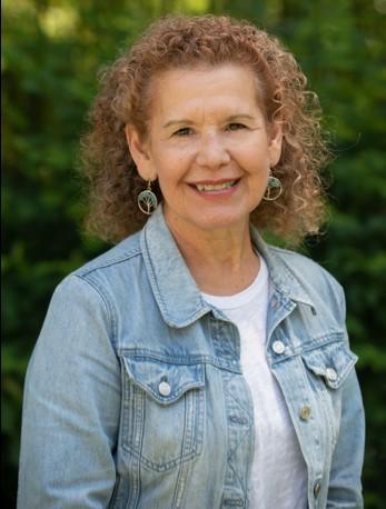 Headshot of a smiling Dr. Cantu wearing a denim jacket over a white t shirt. Her hair is a light brown and curly. 