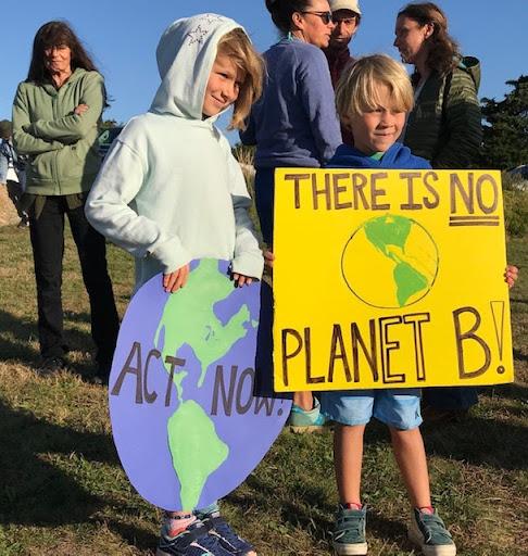  Two kids hold a climate action protest sign that says "there is no planet b"