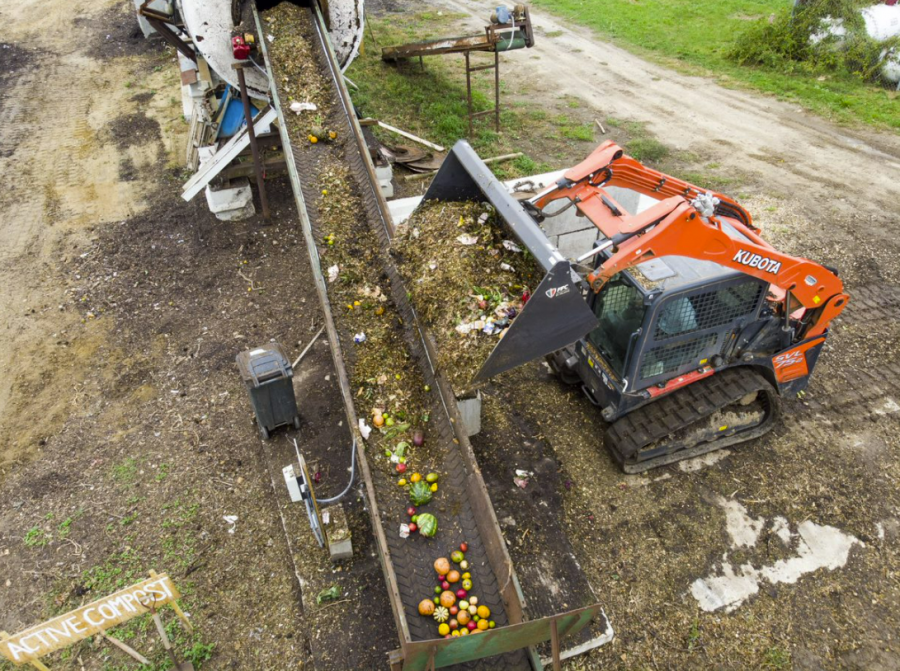 Food waste being loaded into compost pile by tractor.
