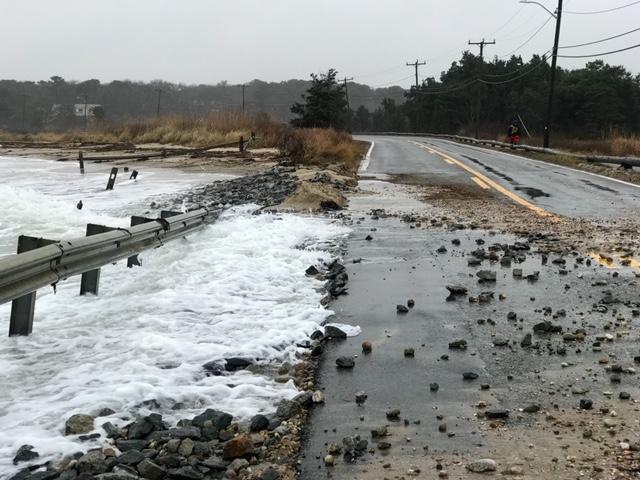 Rocks strewn over a coastal road after a storm.