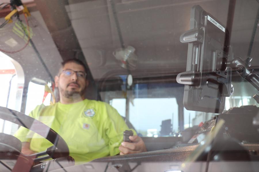 A smart phone mounted in the front window of a waste management vehicle.